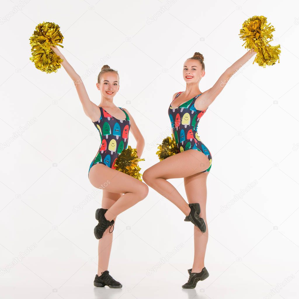 The two of teen cheerleaders posing at white studio