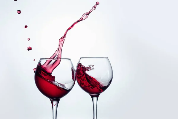 Two wine glasses in toasting gesture with big splashing. — Stock Photo, Image