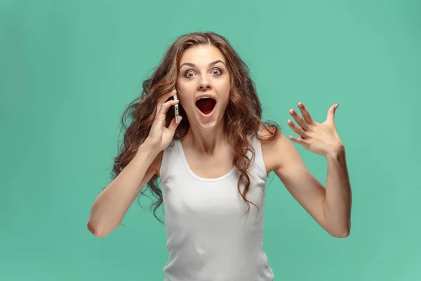 Schockierte Frau blickt auf Handy auf grünem Hintergrund — Stockfoto