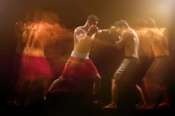 Los dos boxeadores masculinos boxeando en un estudio oscuro — Foto de Stock