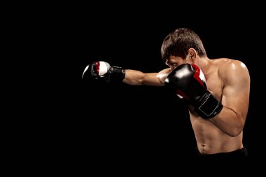 Erkek boxer kum torbası içinde karanlık bir stüdyoda dramatik sinirli aydınlatma ile boks