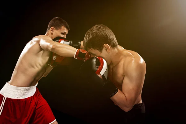 Dos boxeadores profesionales boxeando sobre fondo negro , — Foto de Stock