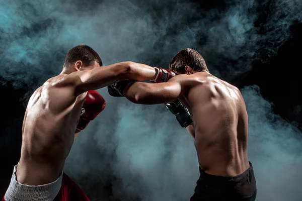 Two professional boxer boxing on black smoky background, — Stock Photo, Image