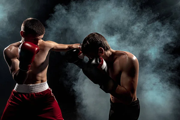 Dos boxeadores profesionales boxeando sobre fondo ahumado negro , — Foto de Stock