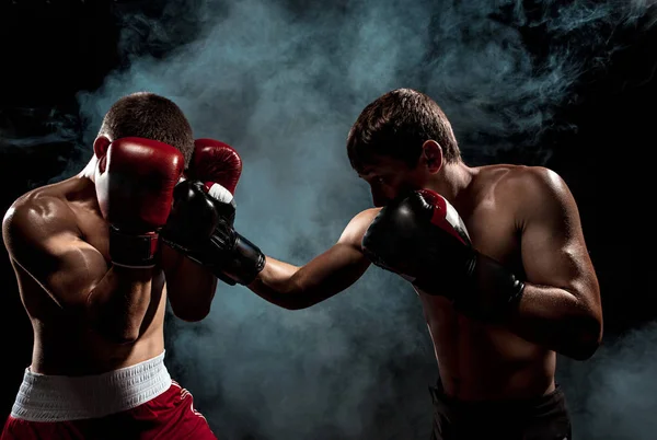 Dos boxeadores profesionales boxeando sobre fondo ahumado negro , — Foto de Stock