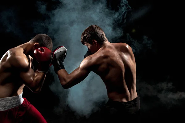 Two professional boxer boxing on black smoky background, — Stock Photo, Image