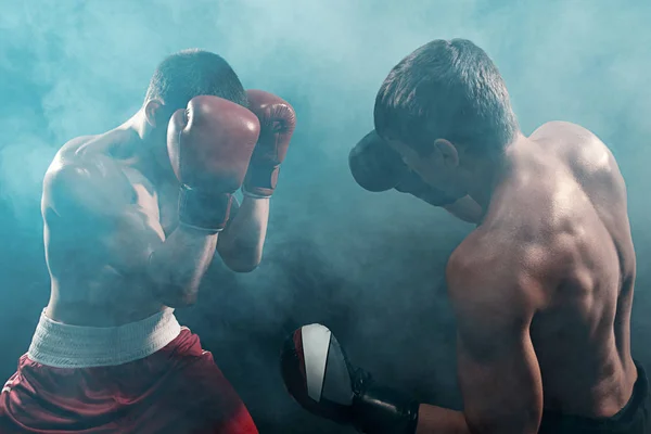 Two professional boxer boxing on black smoky background, — Stock Photo, Image