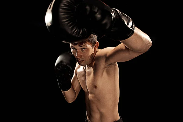 Męski bokser boks w worek treningowy z dramatyczne kanciasty oświetlenia w ciemnych studio — Zdjęcie stockowe