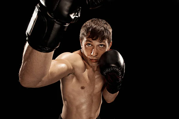 Boxe boxeador masculino em saco de perfuração com iluminação nervosa dramática em um estúdio escuro — Fotografia de Stock