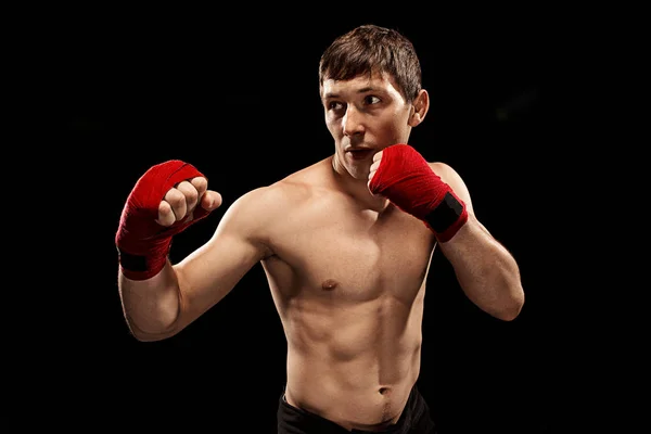 Boxeo boxeador masculino en saco de boxeo con iluminación dramática y vanguardista en un estudio oscuro — Foto de Stock
