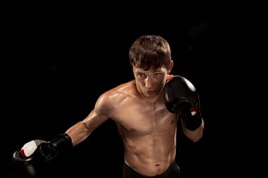 Erkek boxer kum torbası içinde karanlık bir stüdyoda dramatik sinirli aydınlatma ile boks