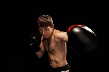 Erkek boxer kum torbası içinde karanlık bir stüdyoda dramatik sinirli aydınlatma ile boks