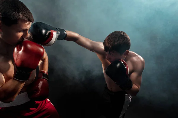 Två professionella boxare boxning på svart rökiga bakgrund, — Stockfoto