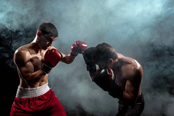 Dos boxeadores profesionales boxeando sobre fondo ahumado negro , — Foto de Stock