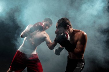 İki profesyonel boksör siyah dumanlı arka planda boks,