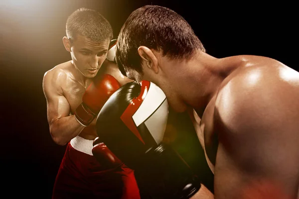 Dos boxeadores profesionales boxeando sobre fondo negro , — Foto de Stock