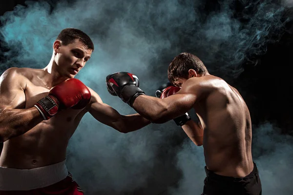 Dos boxeadores profesionales boxeando sobre fondo ahumado negro , — Foto de Stock