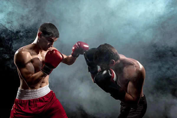 Dos boxeadores profesionales boxeando sobre fondo ahumado negro , — Foto de Stock