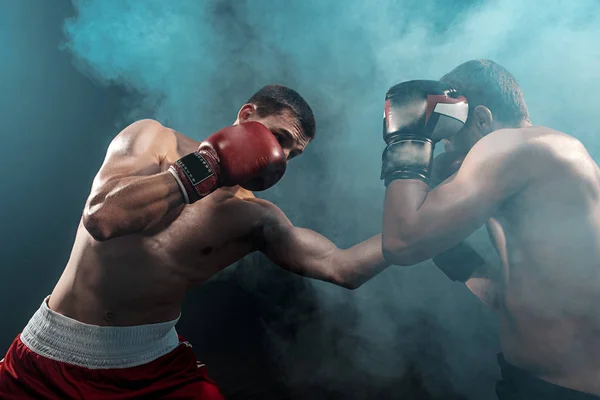 Two professional boxer boxing on black smoky background, — Stock Photo, Image