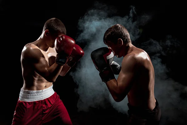 Dos boxeadores profesionales boxeando sobre fondo ahumado negro , — Foto de Stock