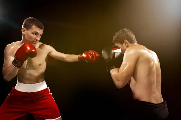 Dos boxeadores profesionales boxeando sobre fondo negro , — Foto de Stock