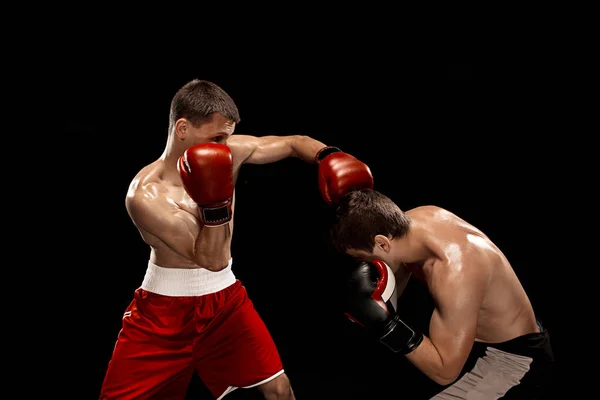 Dos boxeadores profesionales boxeando sobre fondo negro , — Foto de Stock
