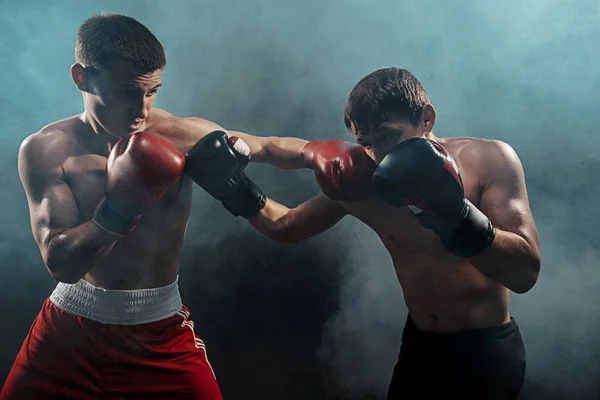 Dos boxeadores profesionales boxeando sobre fondo ahumado negro , — Foto de Stock