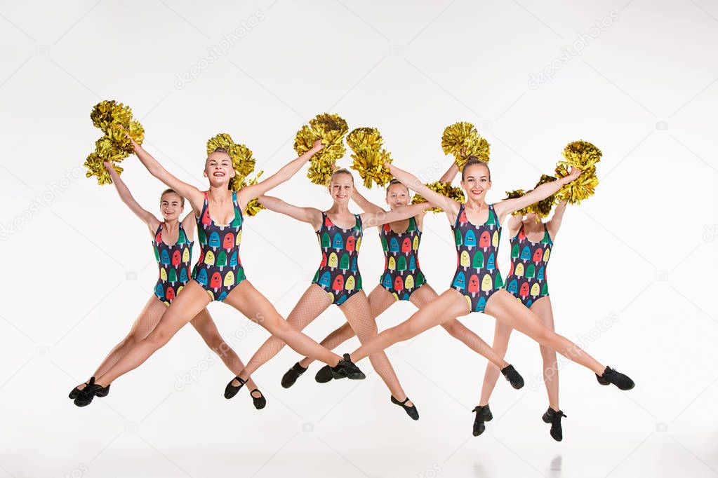 The group of teen cheerleaders jumping at white studio