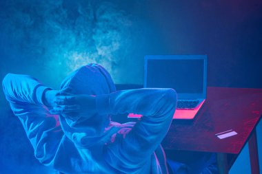 Kapüşonlu bilgisayar korsanı laptopla bilgi çalıyor