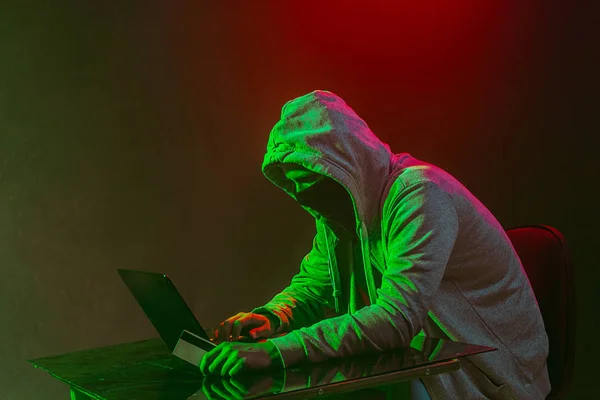 Počítačový hacker s kapucí krade informace s notebookem — Stock fotografie