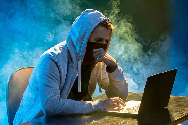 З капюшоном комп'ютерний хакер краде інформацію з ноутбуком — стокове фото