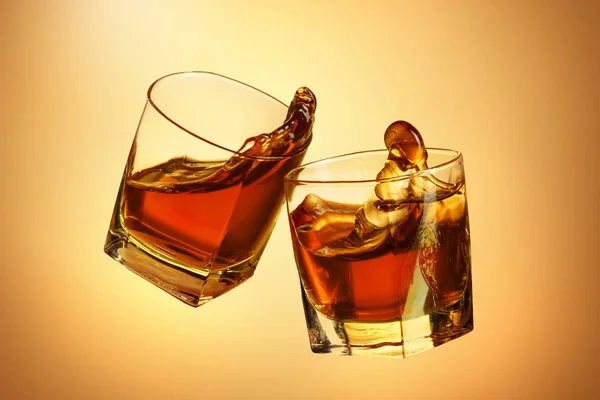 Due bicchieri di whisky che si stringono insieme sul marrone — Foto Stock