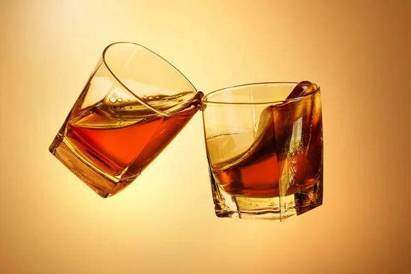 Twee whiskey glazen rammelende samen op brown — Stockfoto