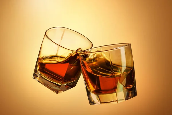Dos vasos de whisky tintinean juntos en marrón — Foto de Stock