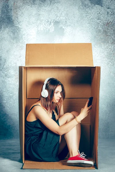 Ввести понятие. Женщина сидит внутри коробки и работает с телефоном — стоковое фото