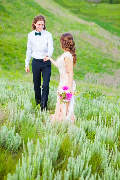 Молодожены влюбленные в свадебном платье на зеленом поле в лесу летом — стоковое фото