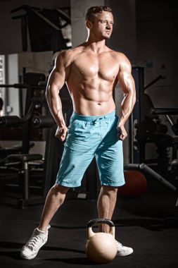 Kaslı vücut geliştirmeci adam ile spor salonunda ağırlık egzersizleri yapıyor