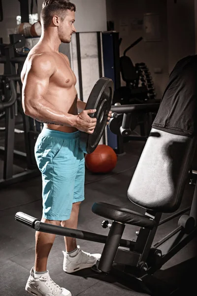 Muscular fisiculturista cara fazendo exercícios com peso no ginásio — Fotografia de Stock