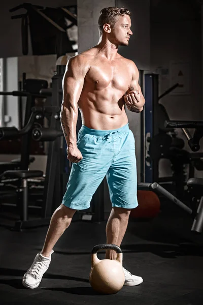 Мышечный культурист парень делает упражнения с весом в тренажерном зале — стоковое фото