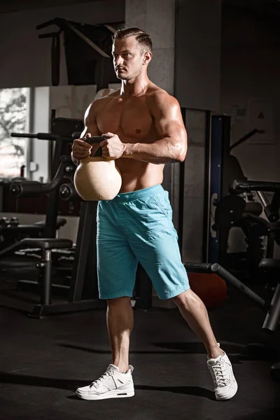 Muscular culturista chico haciendo ejercicios con peso en el gimnasio — Foto de Stock
