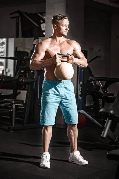 Kaslı vücut geliştirmeci adam ile spor salonunda ağırlık egzersizleri yapıyor