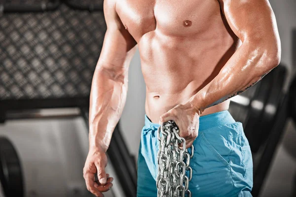 Attractive hunky black male bodybuilder doing bodybuilding pose in gym with iron chains — Stock Photo, Image