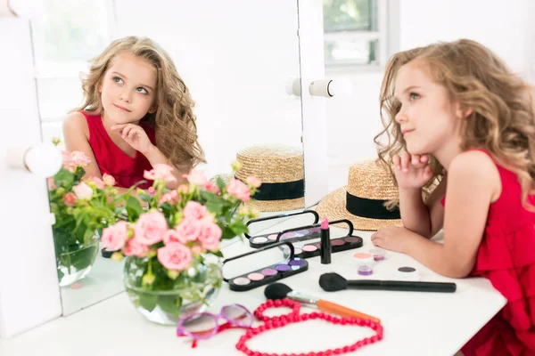 Een klein meisje met cosmetica. Ze is in moeders slaapkamer, zitten in de buurt van de spiegel. — Stockfoto