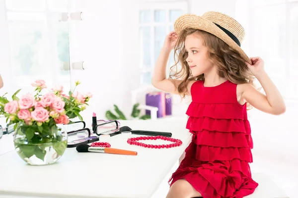Ein kleines Mädchen mit Kosmetik. sie sitzt im Schlafzimmer der Mutter neben dem Spiegel. — Stockfoto