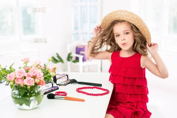 Ein kleines Mädchen mit Kosmetik. sie sitzt im Schlafzimmer der Mutter neben dem Spiegel. — Stockfoto