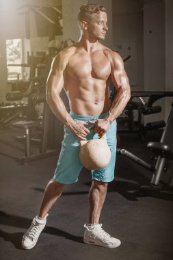 Kaslı vücut geliştirmeci adam ile spor salonunda ağırlık egzersizleri yapıyor