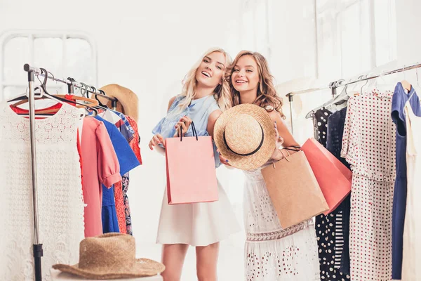 As duas meninas bonitas jovens olhando para vestidos e experimentá-lo ao escolher na loja — Fotografia de Stock