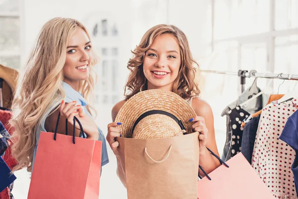 The two young pretty girls looking at dresses and try on it while choosing at shop — Stock Photo, Image
