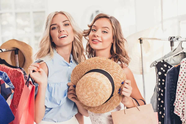 Las dos chicas guapas jóvenes mirando vestidos y probarlo al elegir en la tienda — Foto de Stock