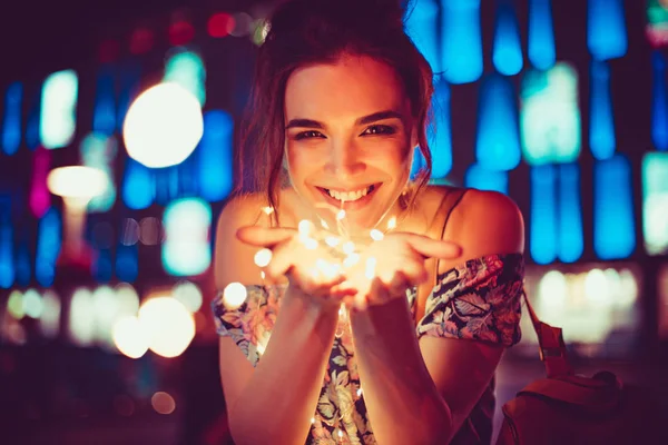 Красивая молодая женщина улыбается и говорит гирлянды огней в городе — стоковое фото